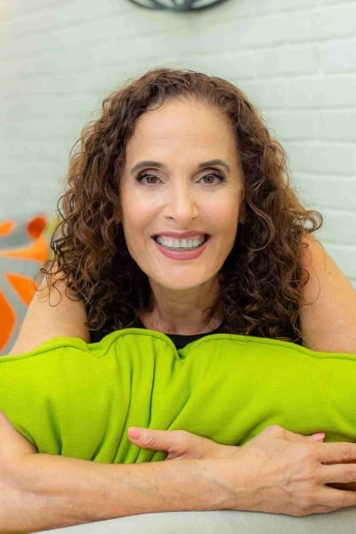 אווה יושבת בספה ומחבקת כרית בצבע ירוק תפוח